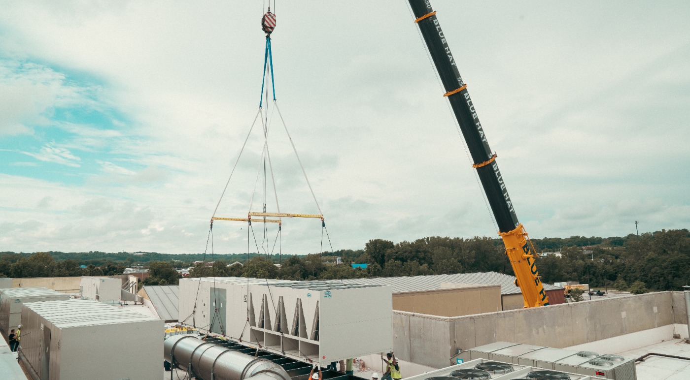 Large crane lifting rooftop units on arena roof